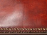 a brown leather suitcase with rivets on it
