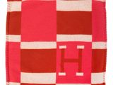 une couverture à carreaux rouges et blancs sur laquelle figure la lettre h