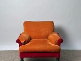 une chaise orange sur laquelle est posé un coussin, dans une pièce