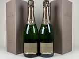 deux bouteilles de champagne posées l'une à côté de l'autre devant une boîte