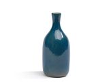 un vase bleu posé sur une surface blanche