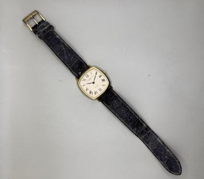gros plan d'une montre sur une surface blanche avec un bracelet noir
