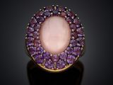 a close up of a ring with a pink stone surrounded by purple stones