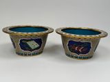 two blue and gold vases with designs on them on a white surface