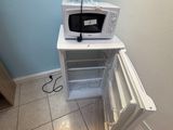 a microwave sitting on top of a refrigerator in the corner of a room
