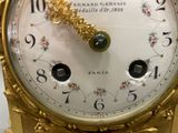a gold clock with a white face and numbers on it