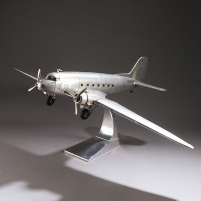 une maquette en argent représentant un petit avion, posée sur un socle