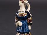une figurine représentant une femme vêtue d'une robe bleue et d'un chapeau