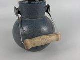 a blue vase with a wooden handle on a table