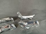 three silver figurines of animals and a bird on a black background