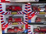 four red and white toy fire trucks in boxes on a white surface