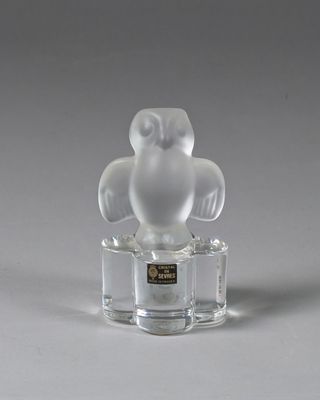 figurine en verre transparent représentant un hibou, posée sur un socle transparent