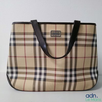 beige and black plaid purse sitting on a table with a white wall
