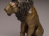 statue of a lion sitting on its hind legs on a gray surface