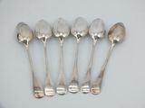 six silver spoons are lined up in a row on a white surface