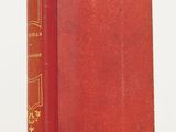 un vieux livre rouge posé sur une table blanche