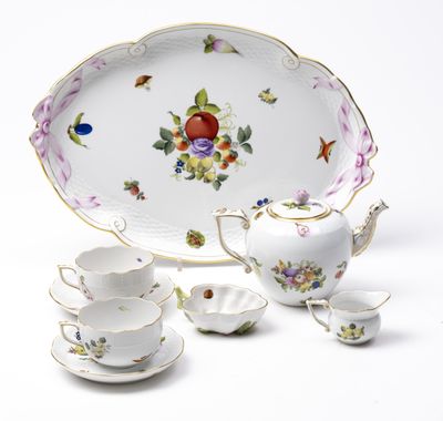 une assiette blanche décorée de fleurs, ainsi qu'une théière et une soucoupe