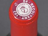 a close up of a wine bottle with a red cap