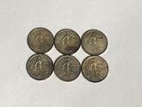 a close up of six coins on a white surface