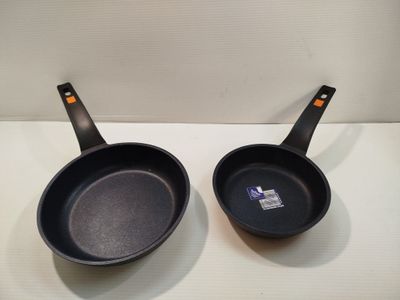 pair of black frying pans sitting on top of a white counter