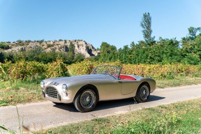une voiture de sport argentée et rouge qui roule sur la route