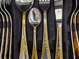 des couverts dans un coffret noir orné de bordures dorées, contenant des couverts