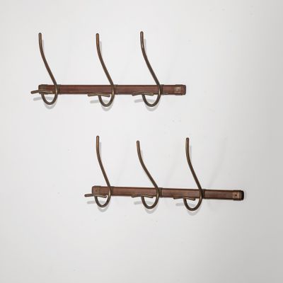trois crochets métalliques sont accrochés à un mur sur fond blanc