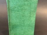 a green book sitting on top of a table next to a gray background