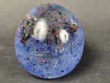 blue and white marble with a black base on a gray surface