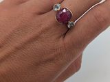 quelqu'un tient une bague sertie d'une pierre rouge