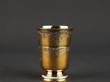 an antique gold cup on a grey background