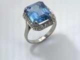 a close up of a ring with a blue stone surrounded by diamonds