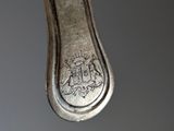 a silver spoon hanging from a string on a gray background