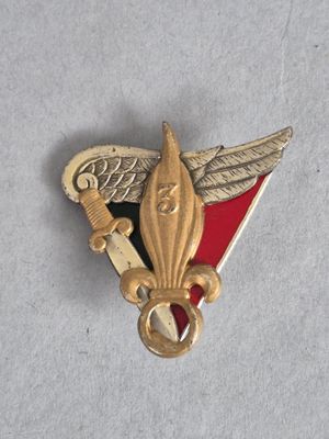 une image représentant une broche dorée et rouge sur laquelle figure un oiseau