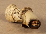 a small figurine of a man with a pipe sticking out of it ' s mouth