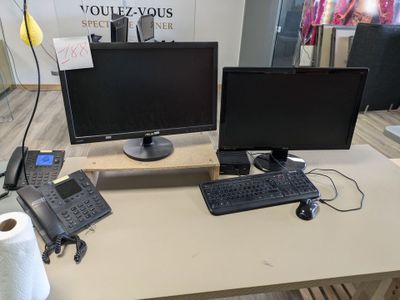 a desk with two monitors and a keyboard on it