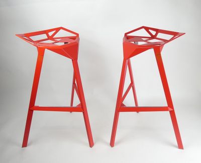 une paire de tabourets en métal rouge sur fond blanc
