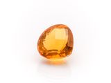 a close up of an orange sapphire stone on a white surface