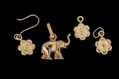 une image représentant un pendentif en forme d'éléphant doré sur fond noir