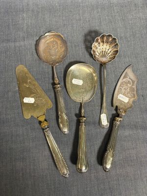 cinq cuillères en métal argenté et un couteau posés sur une table