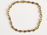 gros plan d'un bracelet en chaîne en or sur une surface blanche