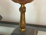a black and gold bowl on a stand on a glass table