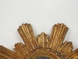 a gold sunburst mirror hanging on the wall