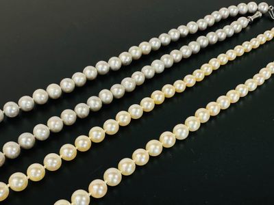 a close up of two strands of pearls on a black surface