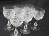 six clear glass goblets are lined up on a black table