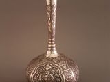 un vase en argent posé sur une table, sur fond marron