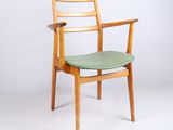 une image représentant une chaise en bois avec une assise verte posée sur un sol blanc