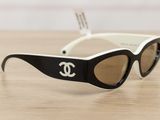 chanel black and white sunglasses with gold lenses on a wooden table