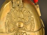 a gold helmet with a red ribbon on it