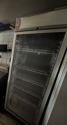 a refrigerator that is open in a kitchen with tile flooring